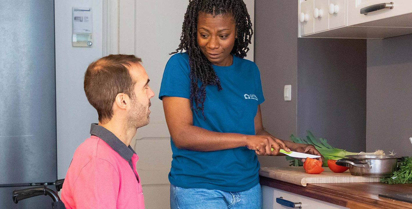 une auxiliaire de vie cuisine pour un homme en fauteuil roulant