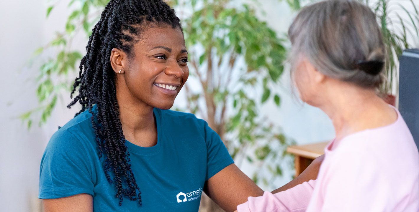 Une auxiliaire de vie est en train de sourire à une femme âgée