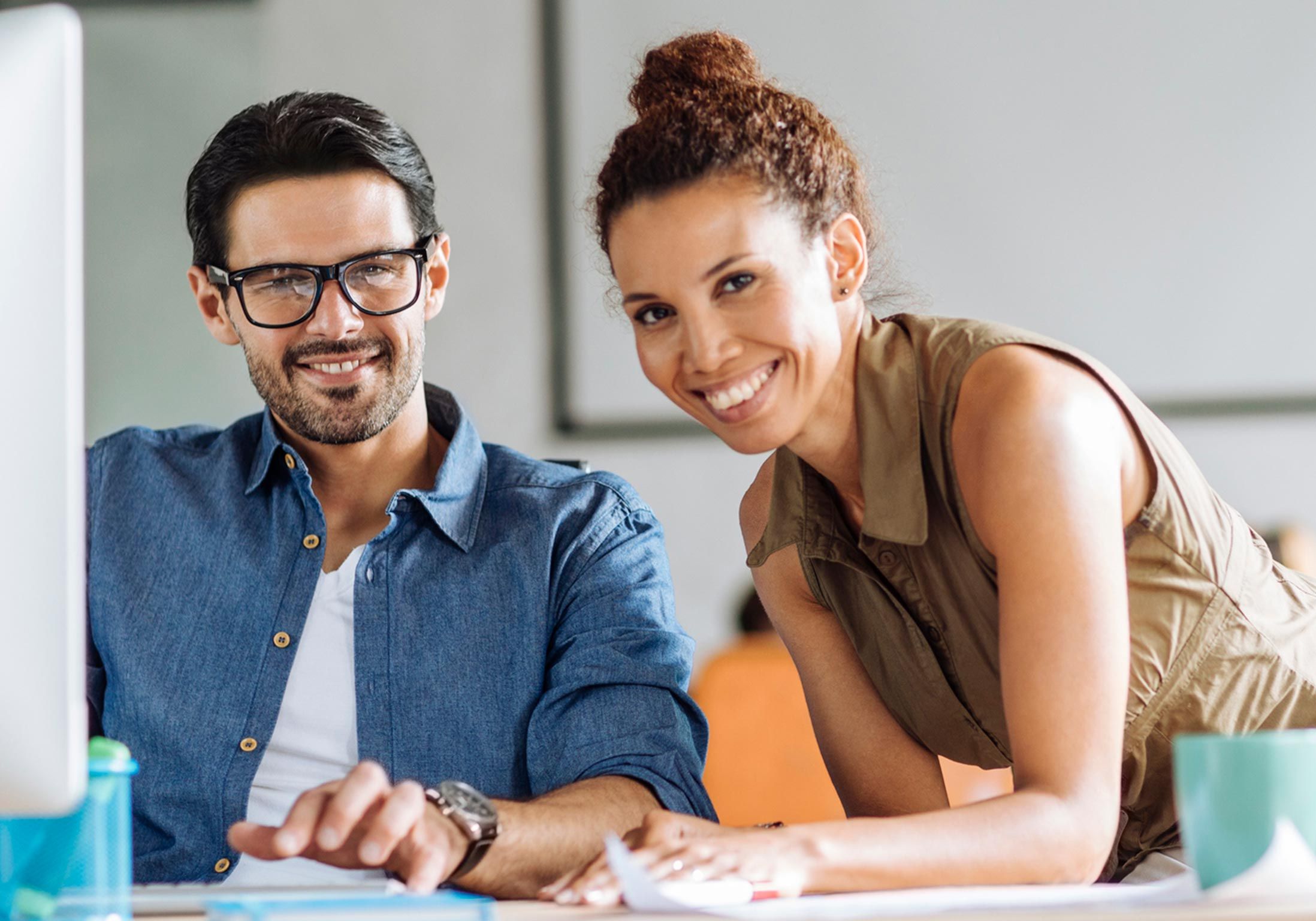 un homme et une femme sont à leur bureau et sourient