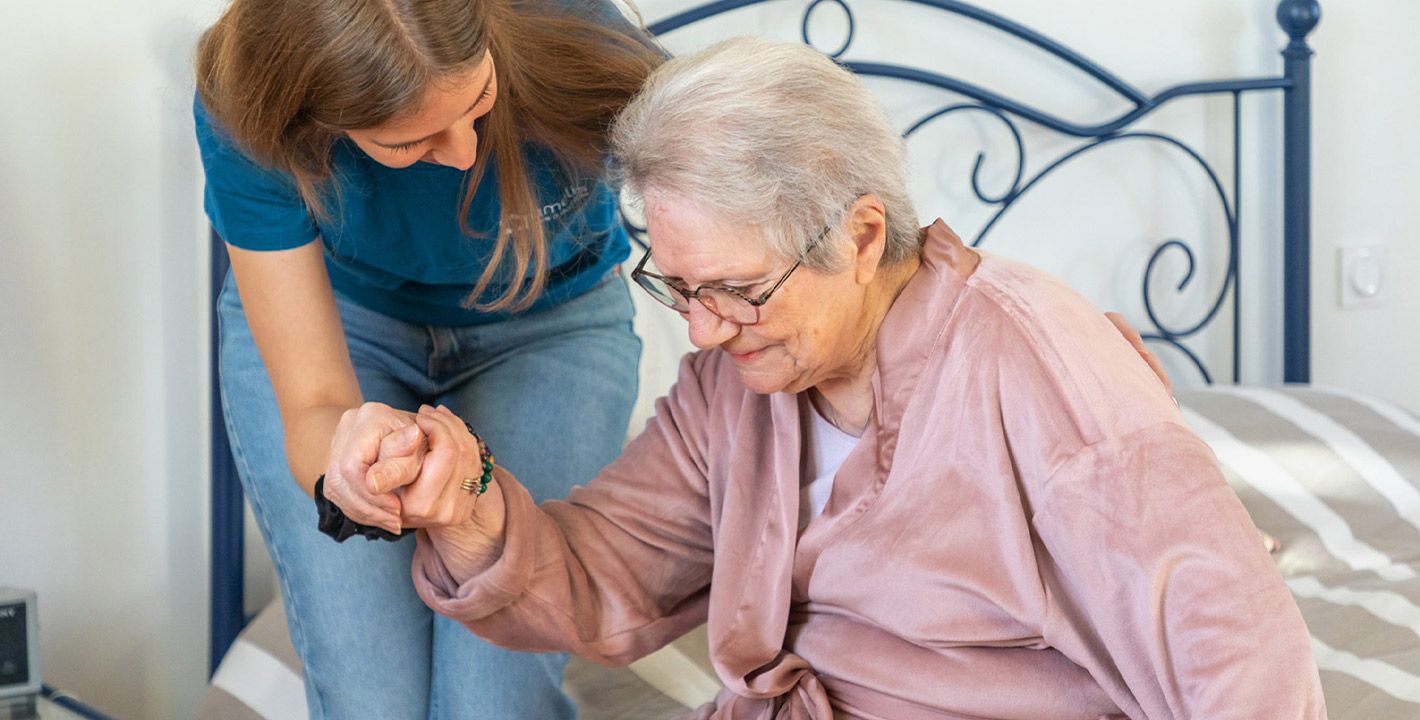 une aide à domicile aide une femme âgée à se lever