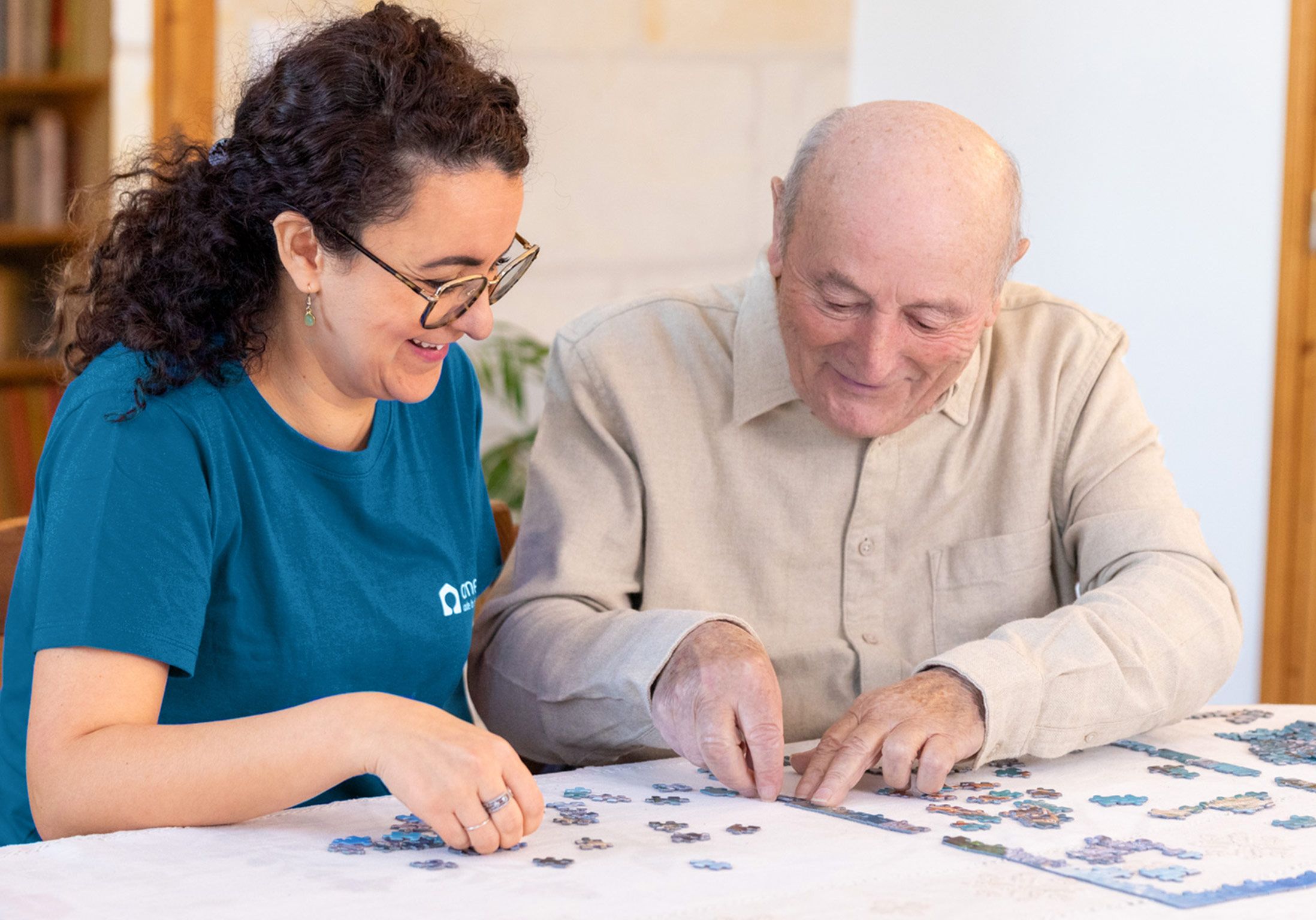 Un homme âgé fait un puzzle avec l'aide de son auxiliaire de vie