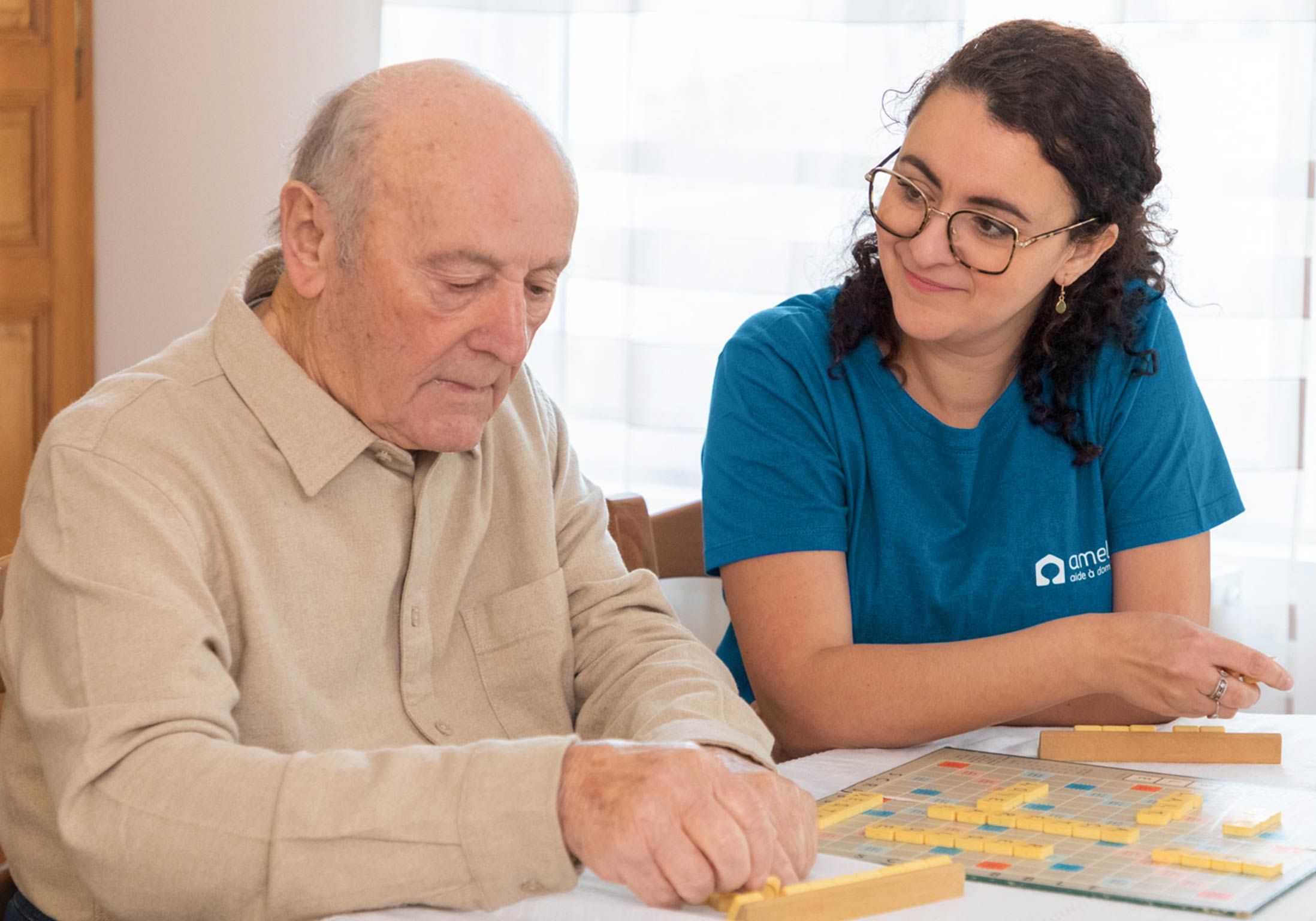 un senior fait un scrabble avec son auxiliaire de vie