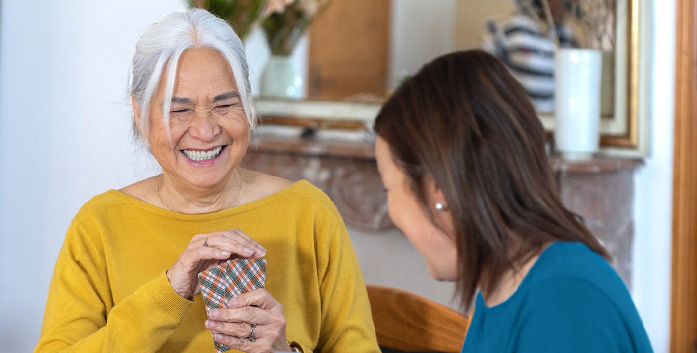 Une femme âgée joue aux cartes avec son aide à domicile