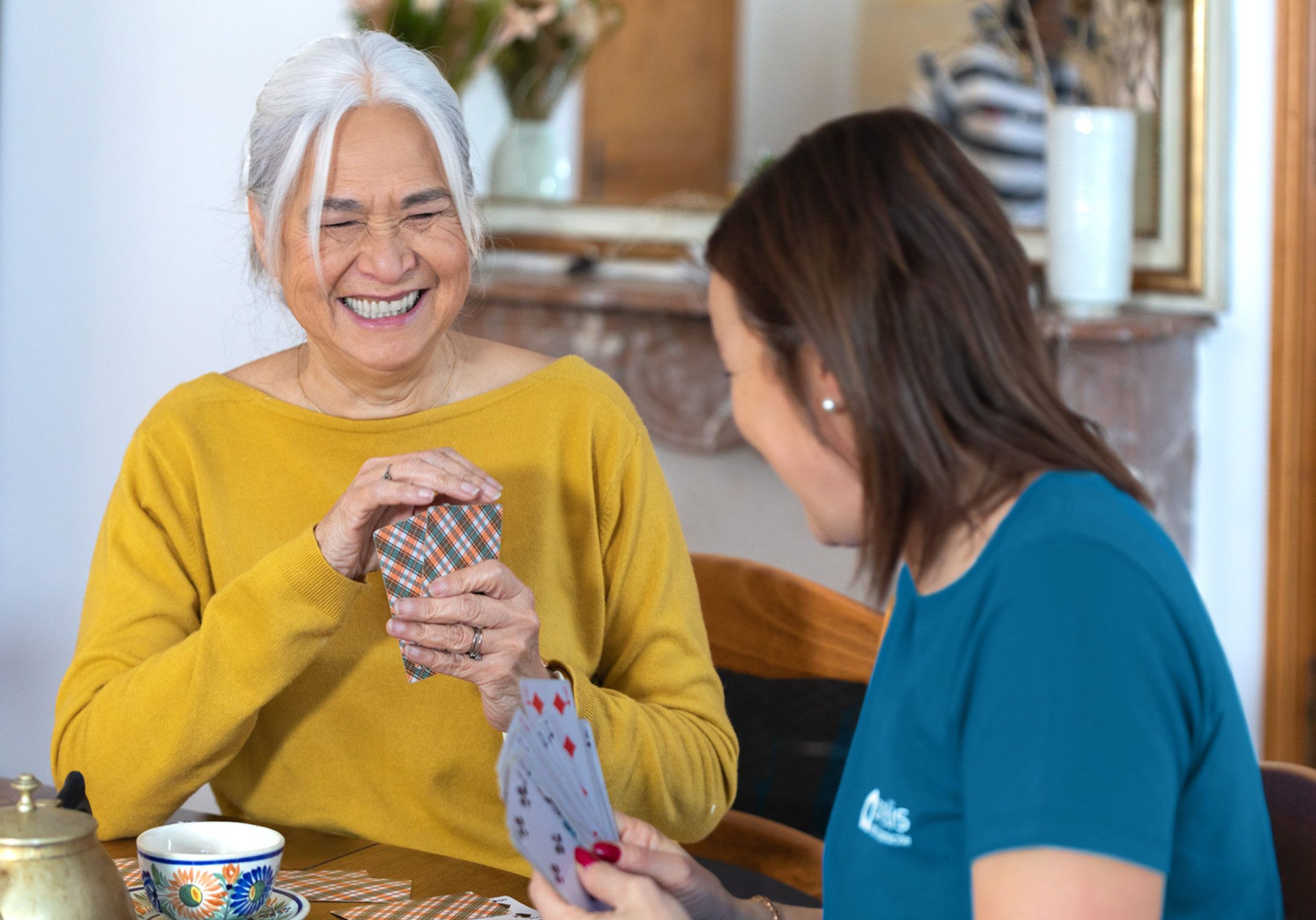 une dame âgée joue aux carte avec son aide à domicile