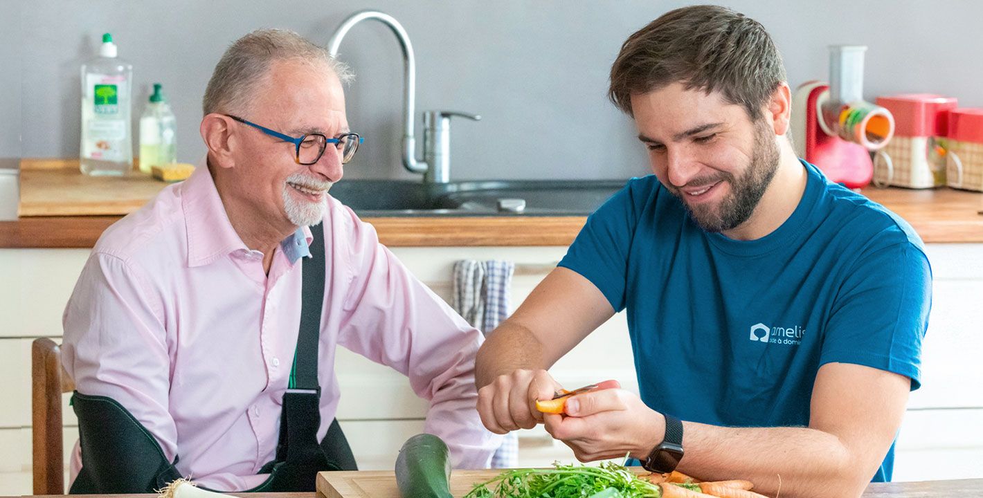 Un homme qui a le bras en écharpe et son aide à domicile cuisinent le repas