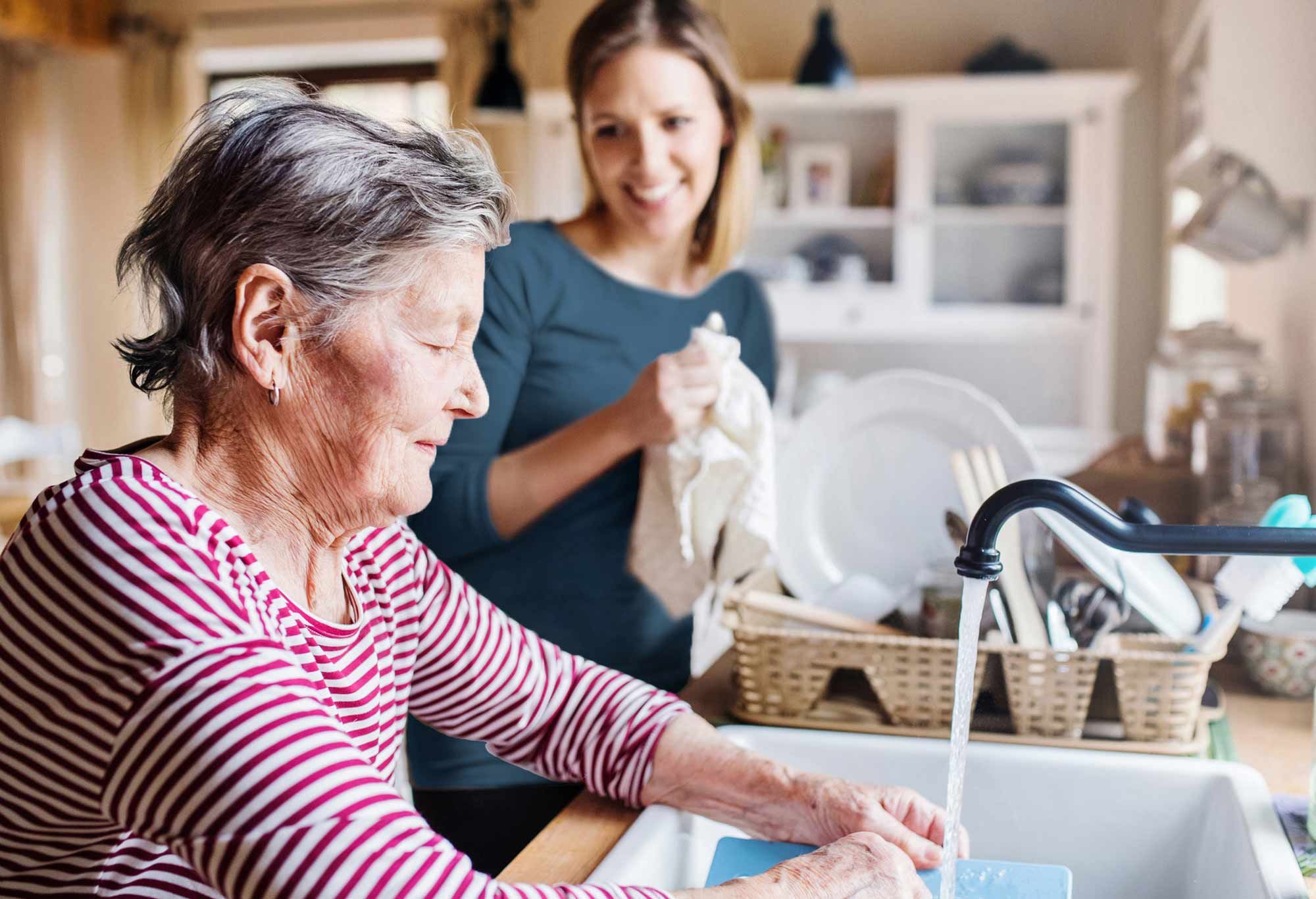 Aide à domicile qui aide une vieille femme à faire la vaisselle