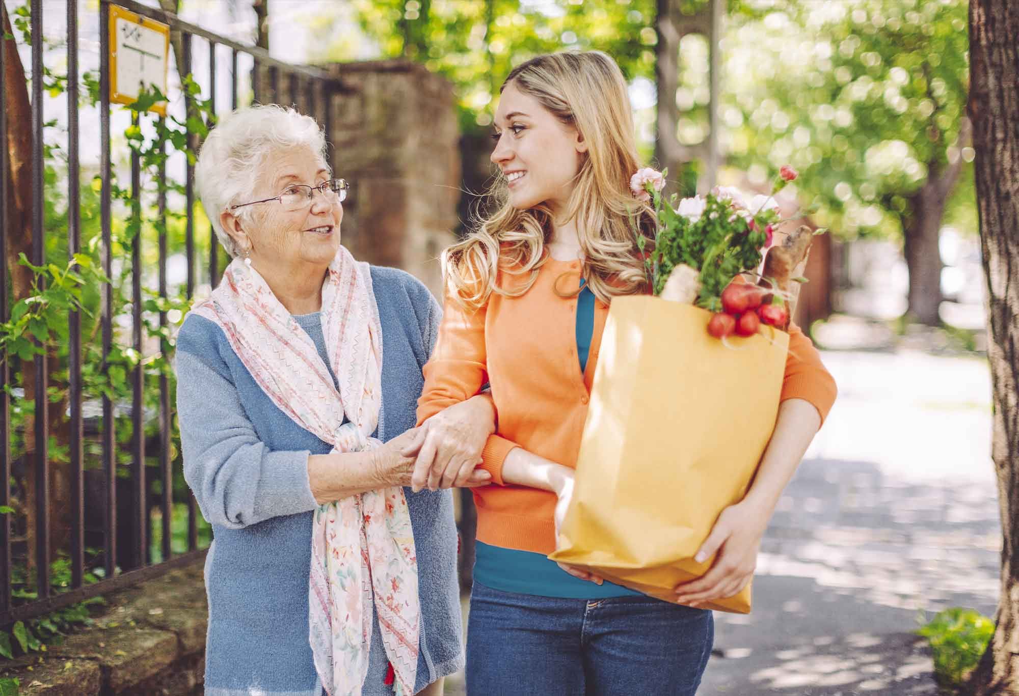 Jeune aide à domicile qui sort faire les courses avec une vieille femme