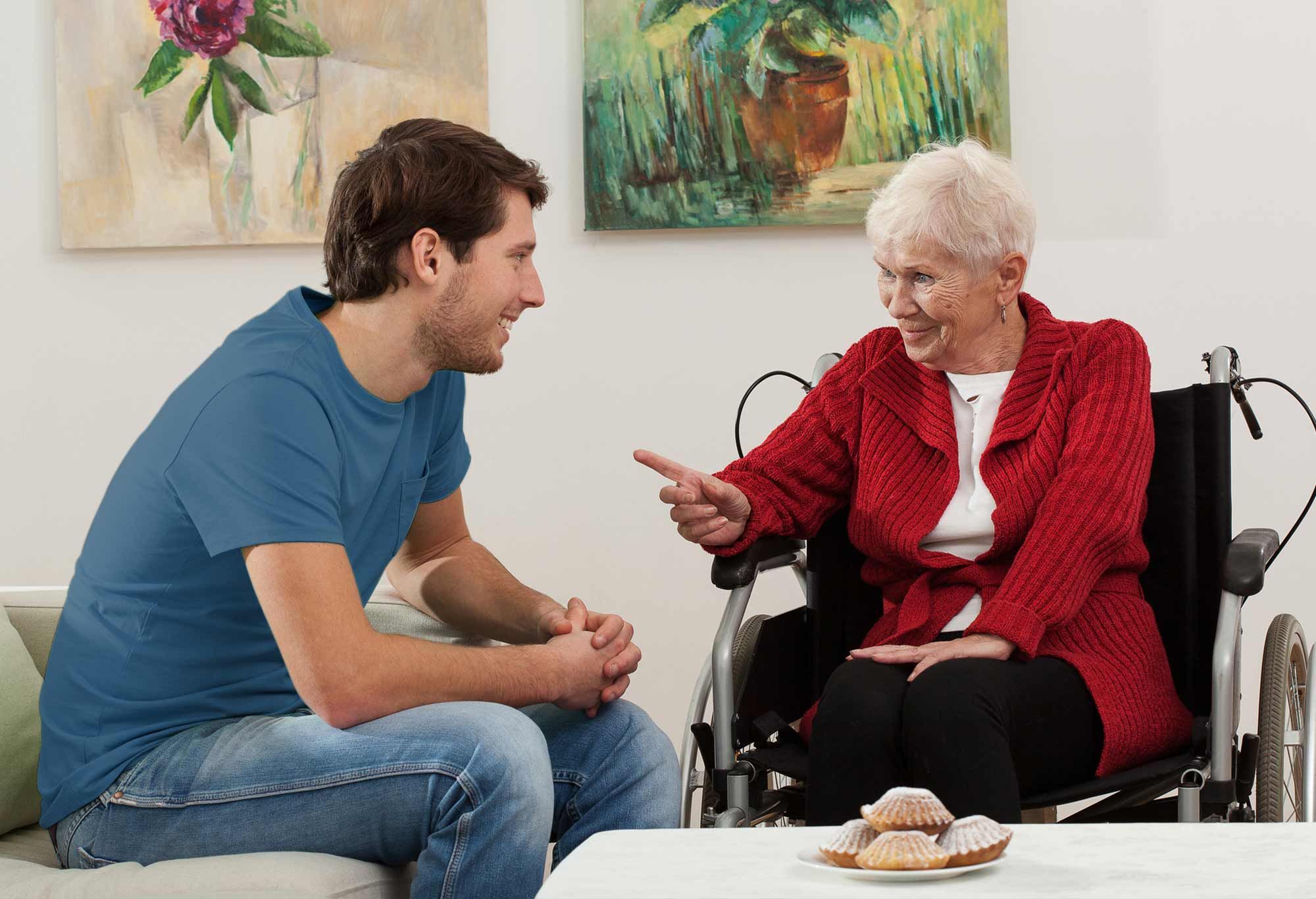 Femme âgée sur son fauteuil roulant qui parle avec son auxiliaire de vie