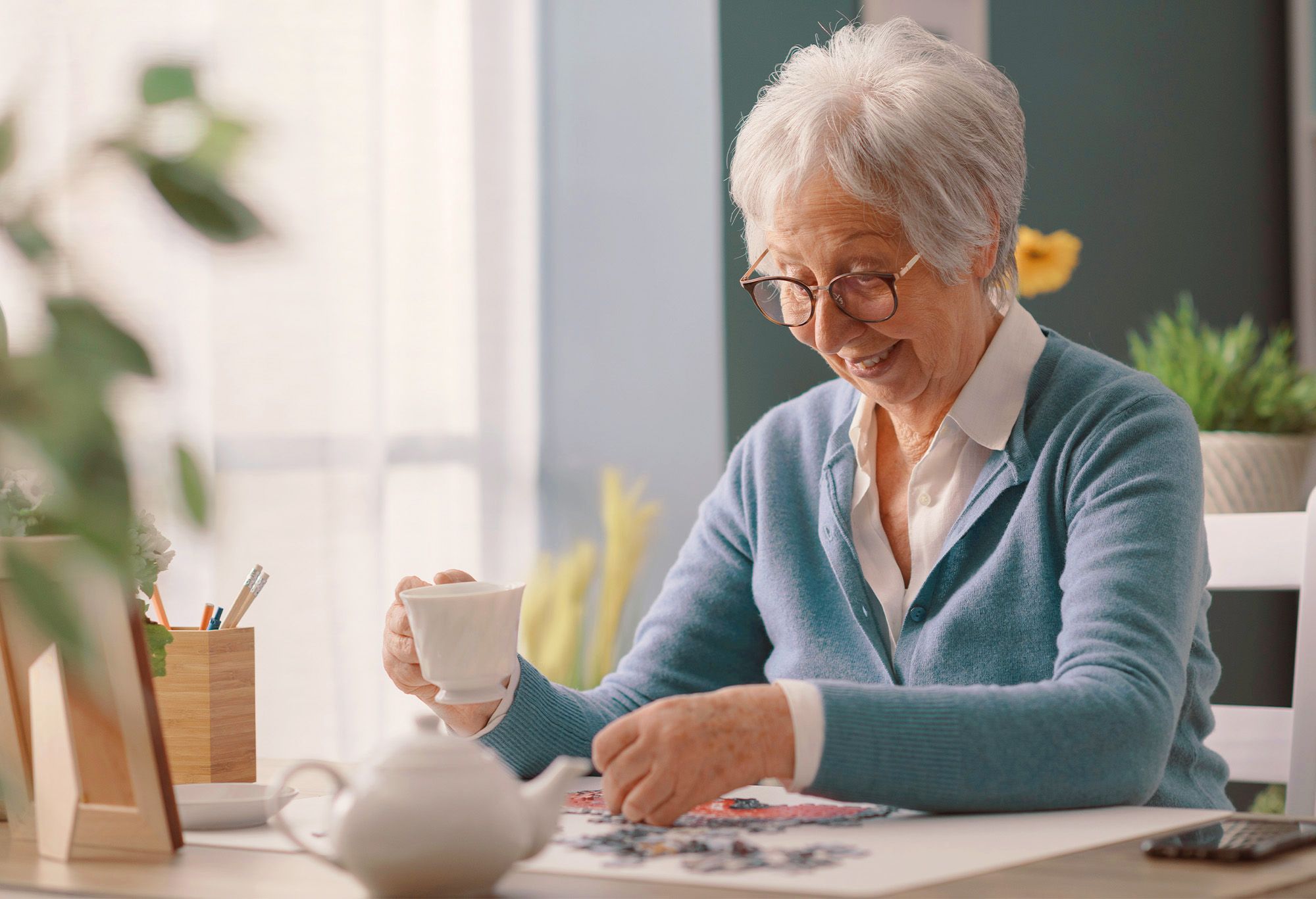 Femme soixante ans prenant le thé et fait un puzzle