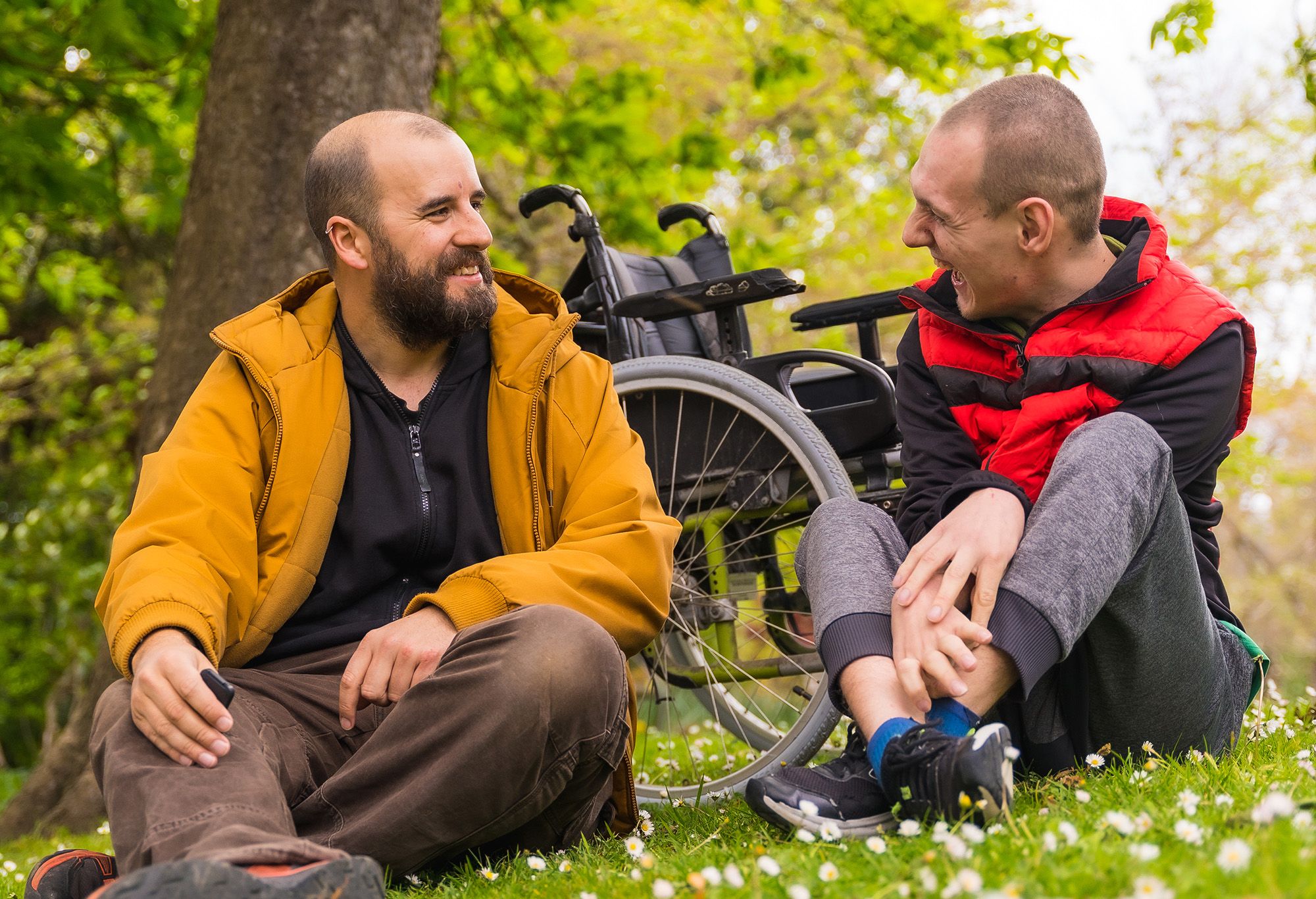 Un homme blanc handicapé en fauteuil roulant qui discute avec son auxiliaire de vie