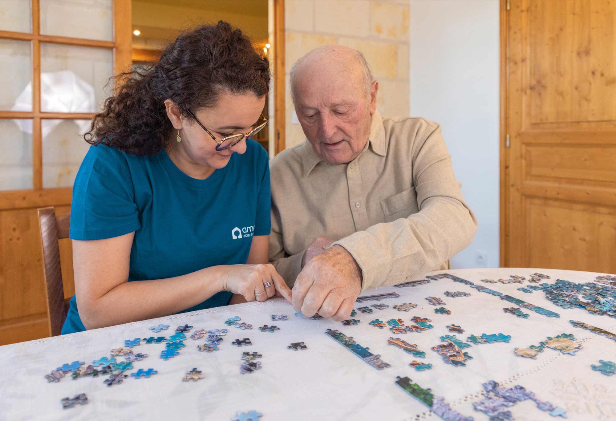 Aide à domicile et homme âgé en train de jouer au puzzle ensemble