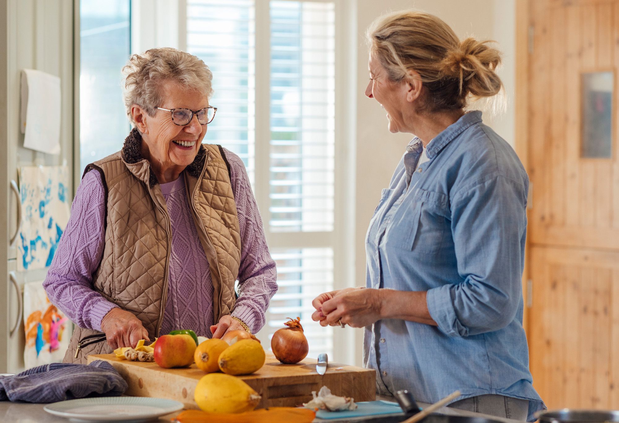 Aide à domicile qui fait le repas avec une vieille femme