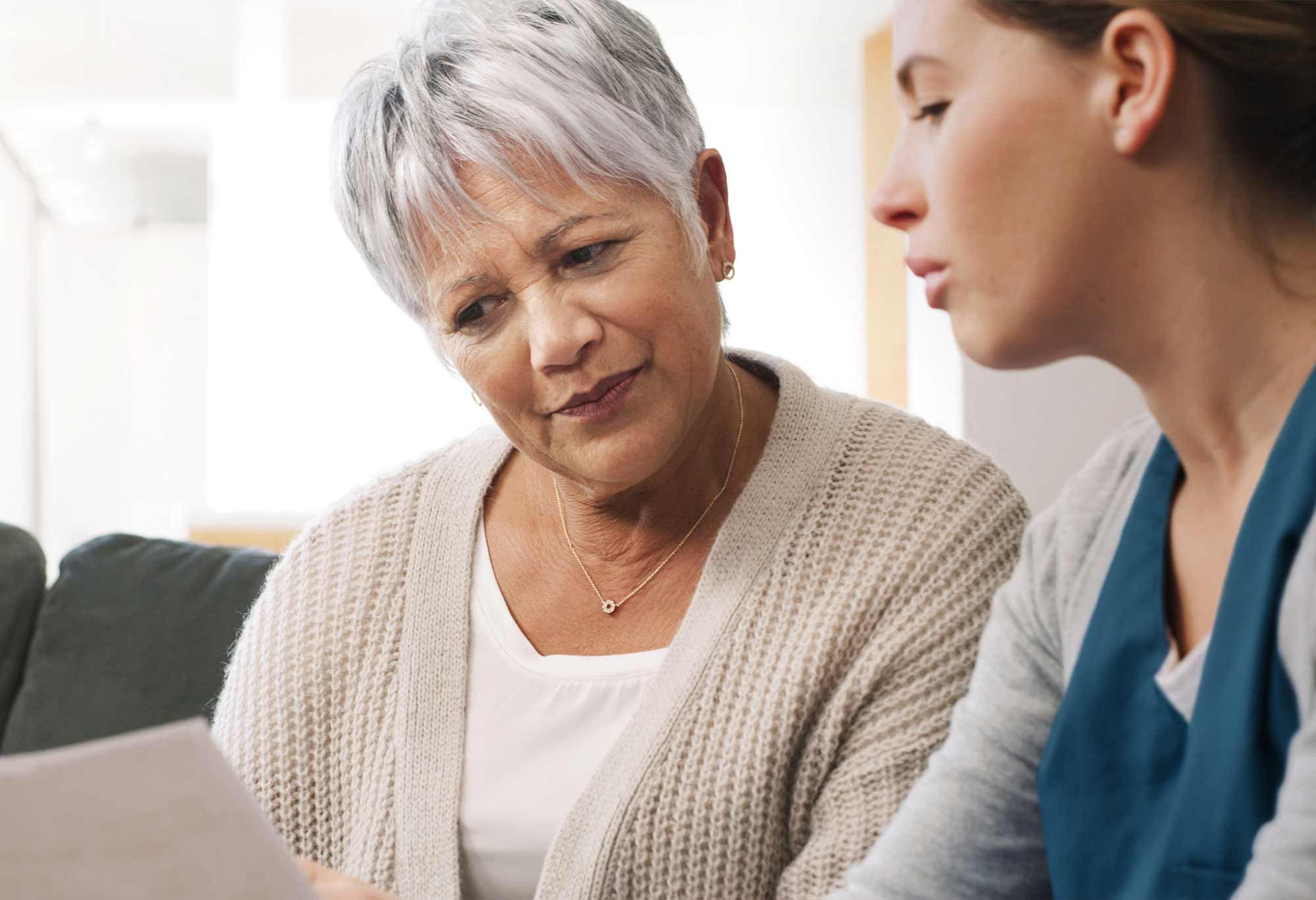 une aide à domicile et une dame âgée lisent un document